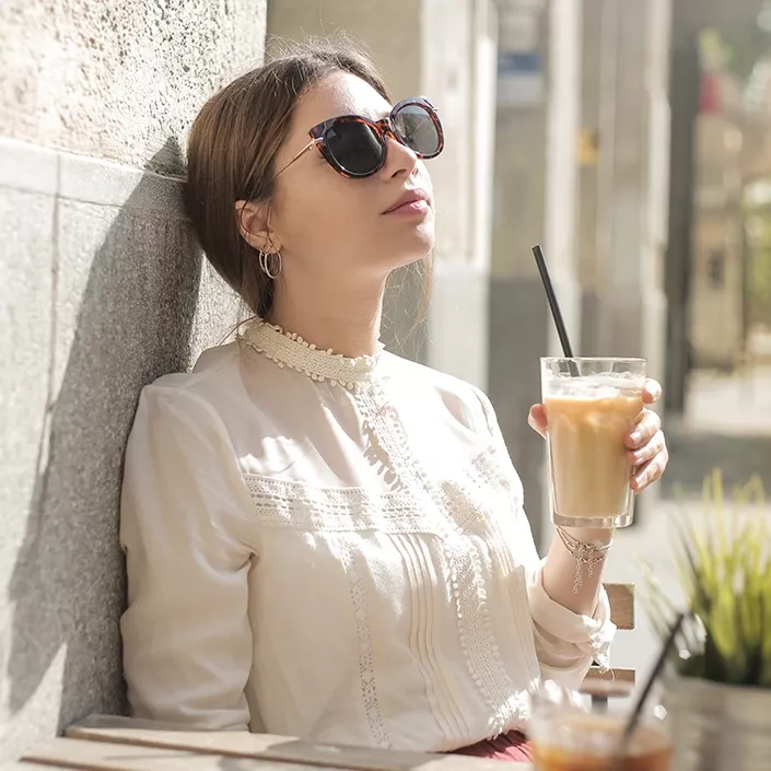 Frau im Café mit Sonnenbrille